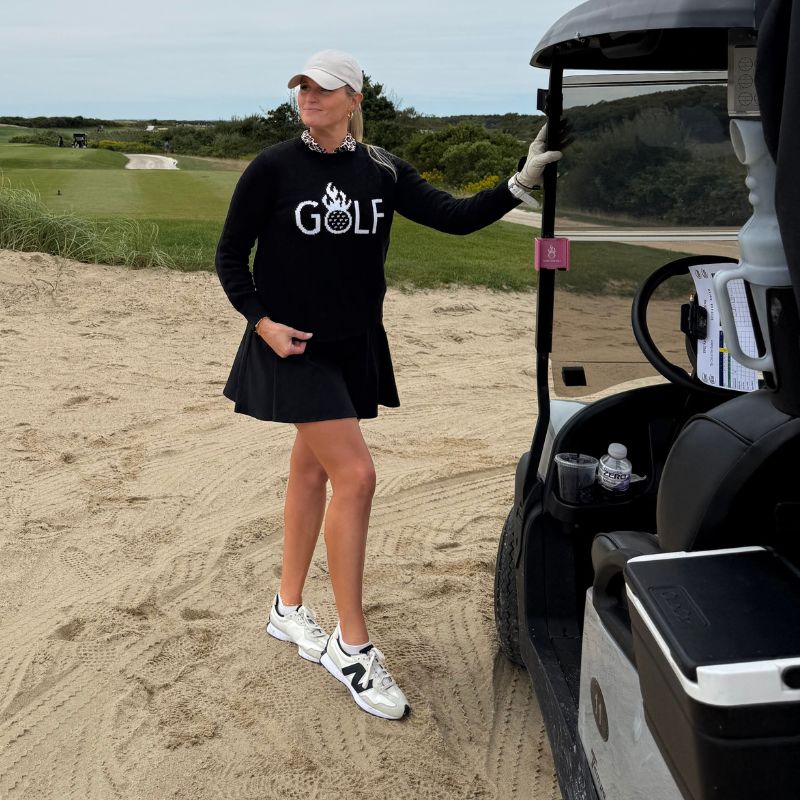 Woman in golf attire standing next to a golf cart on a golf course